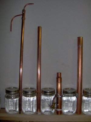 The four pieces<br />Left to right<br />The condenser has a return line that runs down from top to bottom from cap<br />The coolant feed line is tapped into the side of the 1/2&quot; tube<br />A flattened piece of 1/4 tube is tacked on as a band<br />The condenser shell. Just a piece of 3/4&quot; M<br />The slant plate head is detailed in other pic<br />The tower is a 1&quot; pipe with a coupling <br />Will pack with scrubber and build attachment for boiler soon